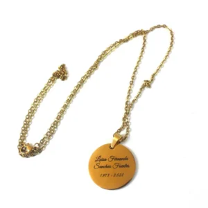 Cadena dorada con dije circular grabado con el nombre y fechas. Joya conmemorativa en acero inoxidable.