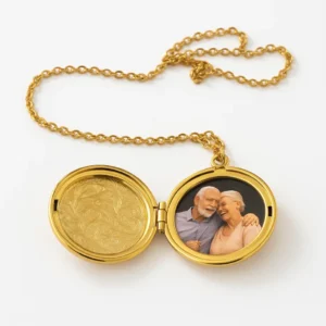 Relicario dorado abierto con fotografía de pareja mayor abrazada, sobre fondo blanco. Joya conmemorativa para llevar memorias cerca del corazón.