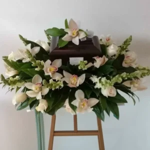 Urna cenizaria con apliques de flores, incluyendo orquídeas y rosas, ideal para conmemorar a un ser querido.